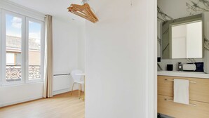 A modern bathroom with a marble countertop, a large mirror, and a towel rack. - Cosy Apartment - 2P - Montreuil (Montreuil)