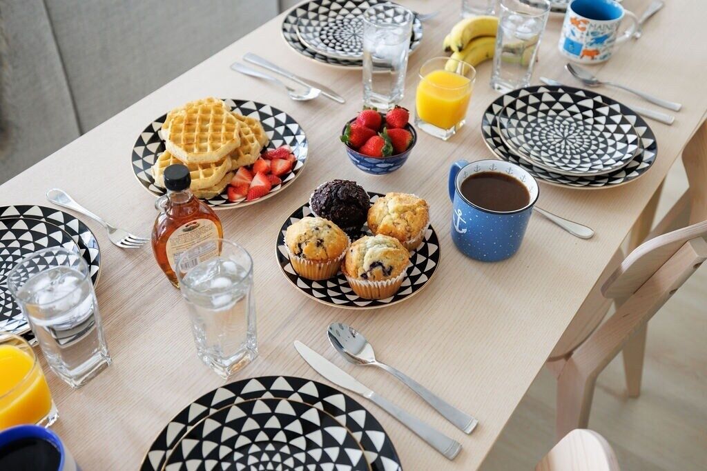 A breakfast table with waffles, muffins, strawberries, and coffee.