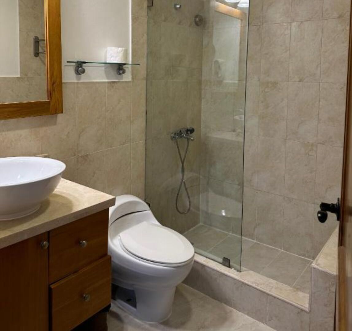 A bathroom with a toilet, a sink, and a glass-enclosed shower.