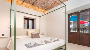 A four-poster bed with a green frame, a window above it, and a view of a balcony with umbrellas. - Room 'Pardo 01' with Balcony, Wi-Fi and Air Conditioning (Catania)