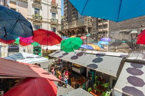 A rooftop bar with multiple umbrellas, outdoor seating, and a view of the cityscape.