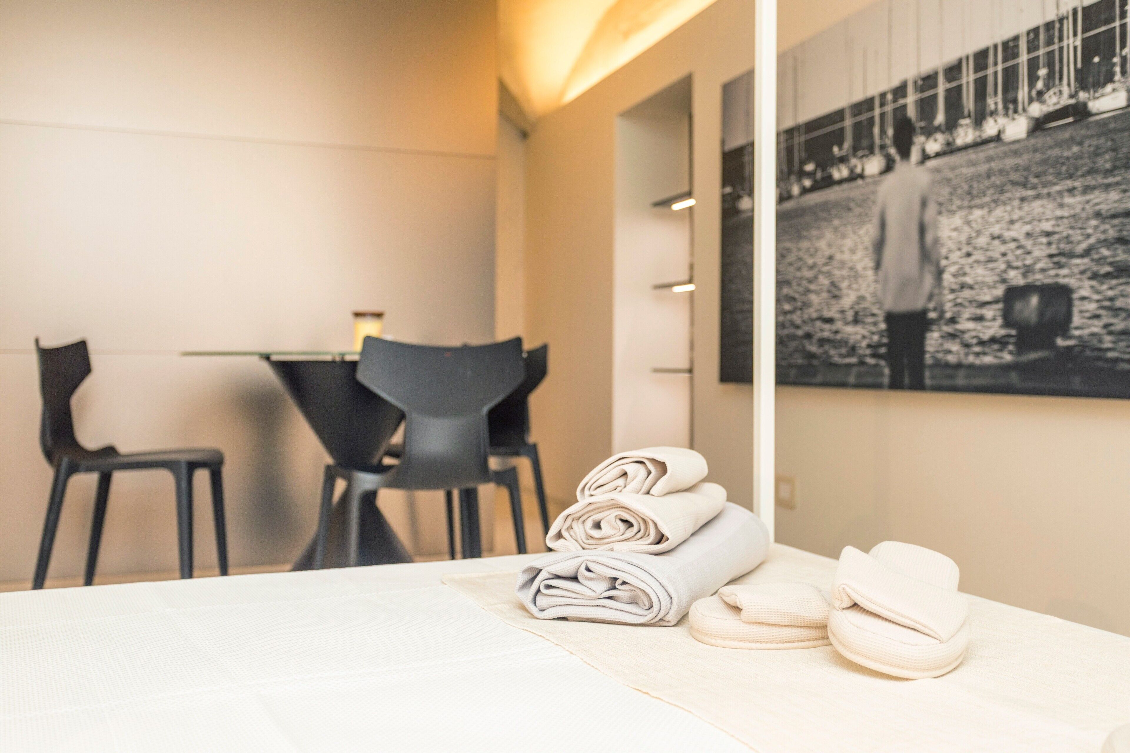 Una habitación de hotel con una cama bien hecha, una mesa de comedor con sillas y un cuadro grande en la pared.