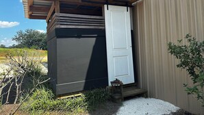 A small, dark-colored building with a white door and a wooden structure above it.
