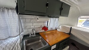 A compact kitchenette with a sink, a wooden countertop, and a small cabinet.