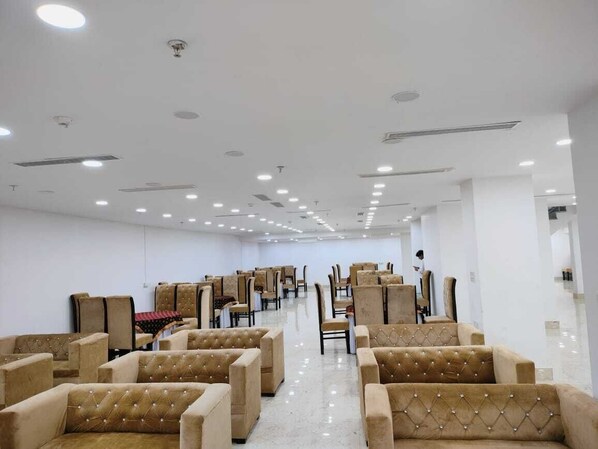 A spacious room with rows of beige upholstered chairs and a polished floor, arranged for seating. - Hotel The Anvi Residency Sector 132 (Noida)