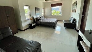 A spacious bedroom with a large bed, a desk, a chair, and a wardrobe. - Peaceful 3BR Villa Near Golf & Beach - Jacuzzi, BBQ & Pool Table (Muang Pattaya)