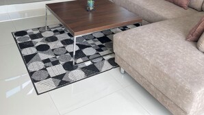 Un salon moderne avec un escalier, un canapé, une table basse et une cuisine en arrière-plan.