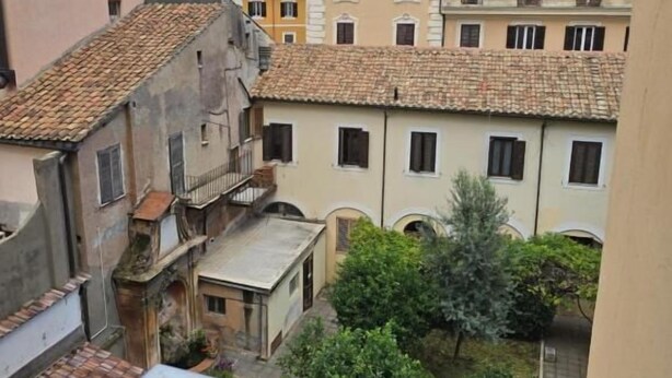 A view of a courtyard with buildings surrounding it, featuring balconies and tiled roofs. - Chez Liviana (Rome)