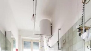 A modern bathroom with a bathtub, a sink, and a toilet. There is a window providing natural light and a small refrigerator in the corner. - Chez Liviana (Rome)