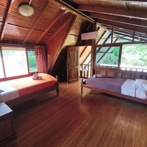 Une pièce avec deux lits en bois, un plafond en bois et de grandes fenêtres.