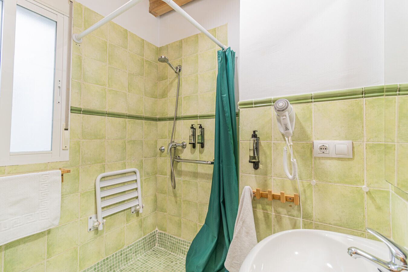 A bathroom with a shower, a hairdryer, and a sink.