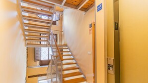 Un escalier avec des marches en bois et des rampes en métal, menant à un ascenseur.