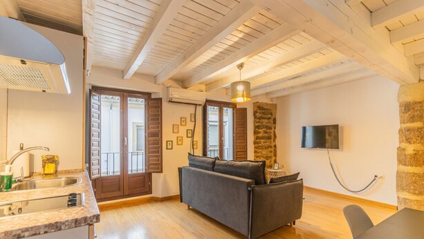 Um apartamento moderno com cozinha, sala de estar com sofá, mesa de jantar e parede de pedra.