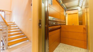 Um elevador com painel de controle, corrimão de madeira e piso coberto de carpete.
