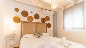 Uma cama bem arrumada com toalhas dobradas, uma luminária de cabeceira e círculos decorativos de fibra na parede.