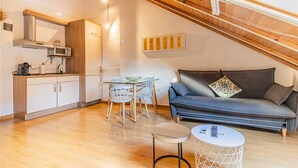 Una cocina moderna con microondas, estufa y armarios. Hay una mesa de comedor con sillas y un sofá en la sala.