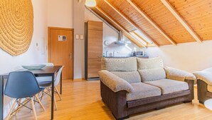 Une pièce confortable de style loft, avec un plafond en bois, une kitchenette, un canapé et un coin repas.