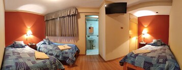 A hotel room with two beds, a television, a bathroom visible through an open door, and a telephone on the nightstand.
