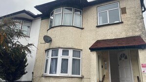A two-story house with a satellite dish, a garage door, and a sign indicating no parking. - London flat close to Wembley stadium easy access to central London garden (London)