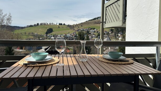 A wooden table with two bowls and two wine glasses on a balcony overlooking a village. - Vacation apartment "SchwarzwaldnACHT" - peace & nature in Todtnauberg - Mein SWH (Todtnauberg)