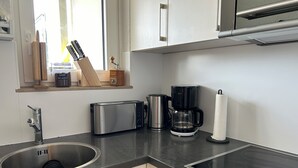 A modern kitchen with a stainless steel sink, a toaster, a coffee maker, and a window with natural light. - Vacation apartment "SchwarzwaldnACHT" - peace & nature in Todtnauberg - Mein SWH (Todtnauberg)