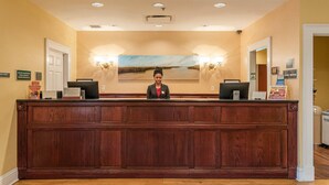 A reception desk with a wooden finish, two computer monitors, and a framed landscape painting above. - Natchez Grand Hotel (Natchez)