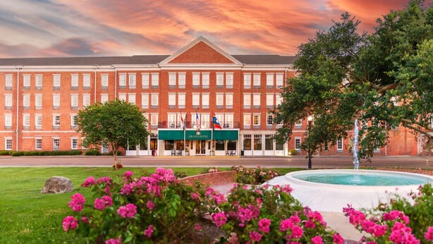 A large brick building with a green awning and a fountain in the foreground. - Natchez Grand Hotel (Natchez)