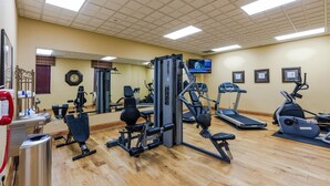A gym with various exercise equipment, a clock, and a television on the wall. - Natchez Grand Hotel (Natchez)
