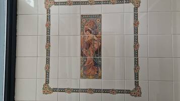 A tiled wall with a central framed artwork depicting a figure in a landscape.
