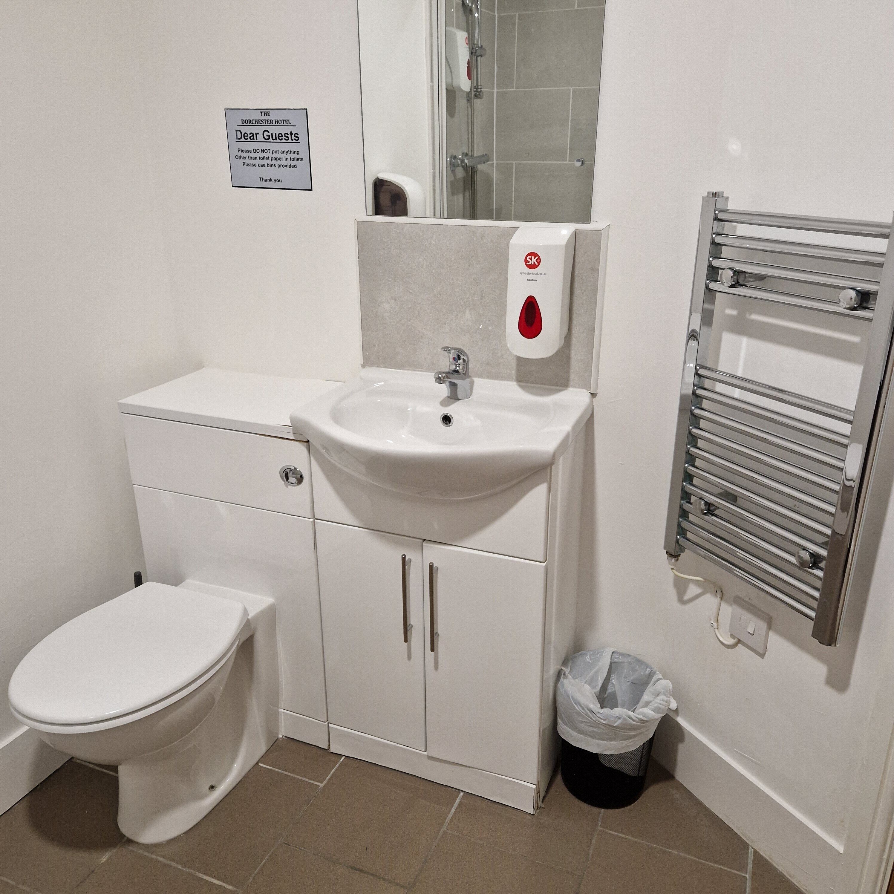 Un bagno con un WC, un lavandino, uno specchio e un portasciugamani.