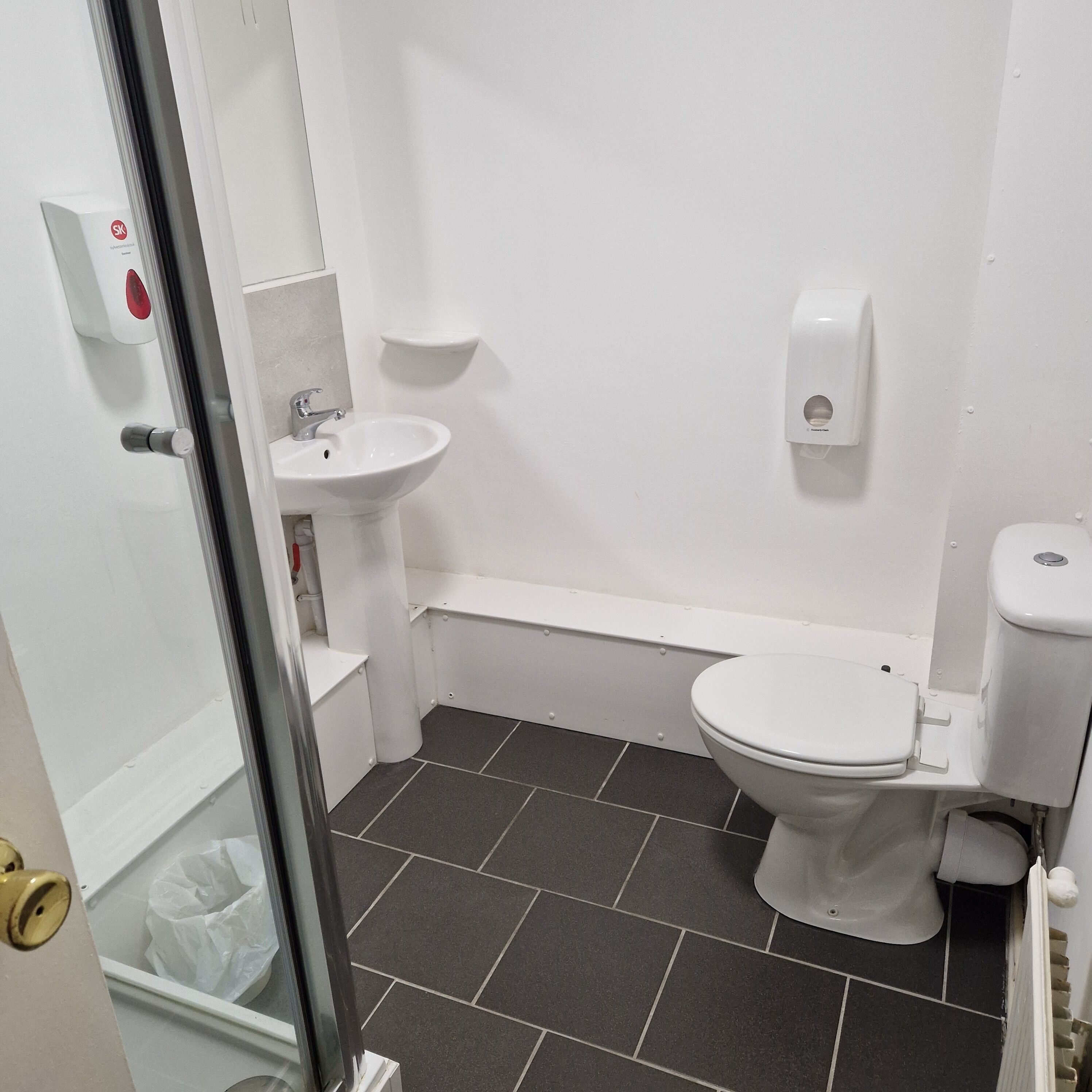 A small, clean bathroom with a toilet, sink, and hand dryer.