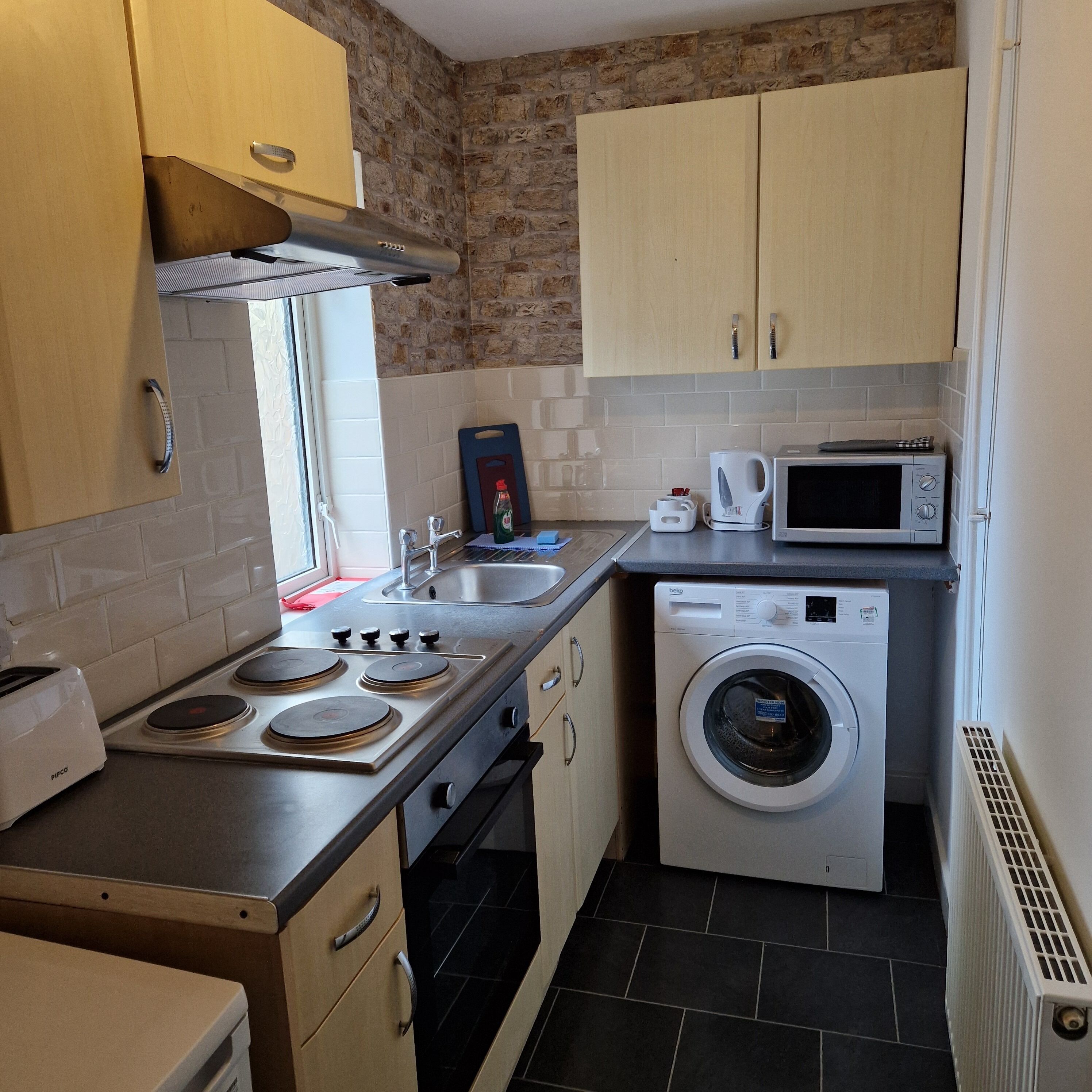 A compact kitchen with a stove, microwave, and washing machine.