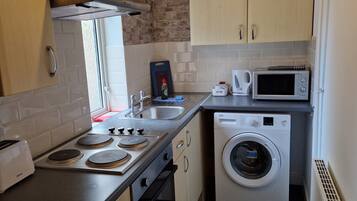 A compact kitchen with a stove, microwave, and washing machine.