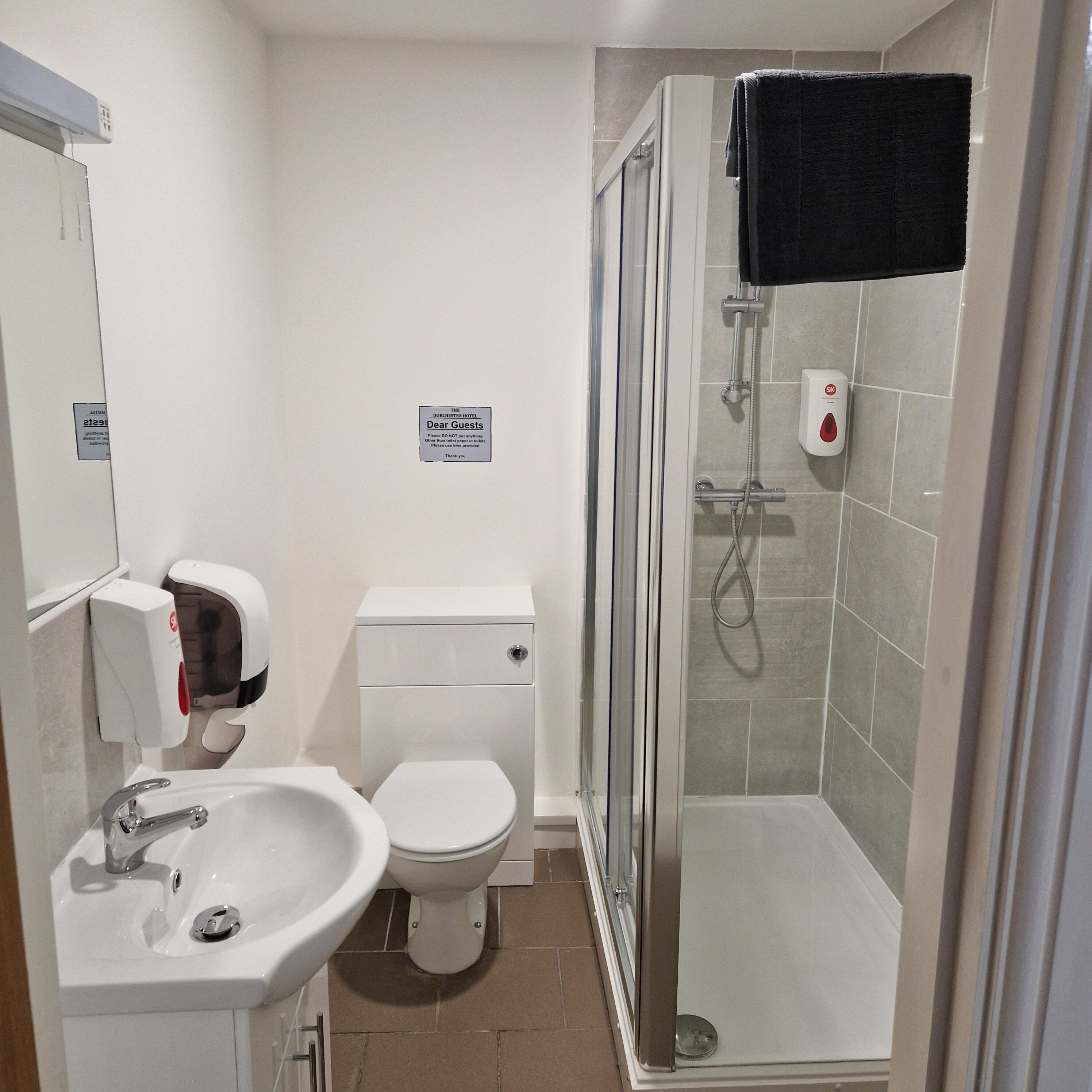 A hotel bathroom with a sink, toilet, and glass-enclosed shower area.