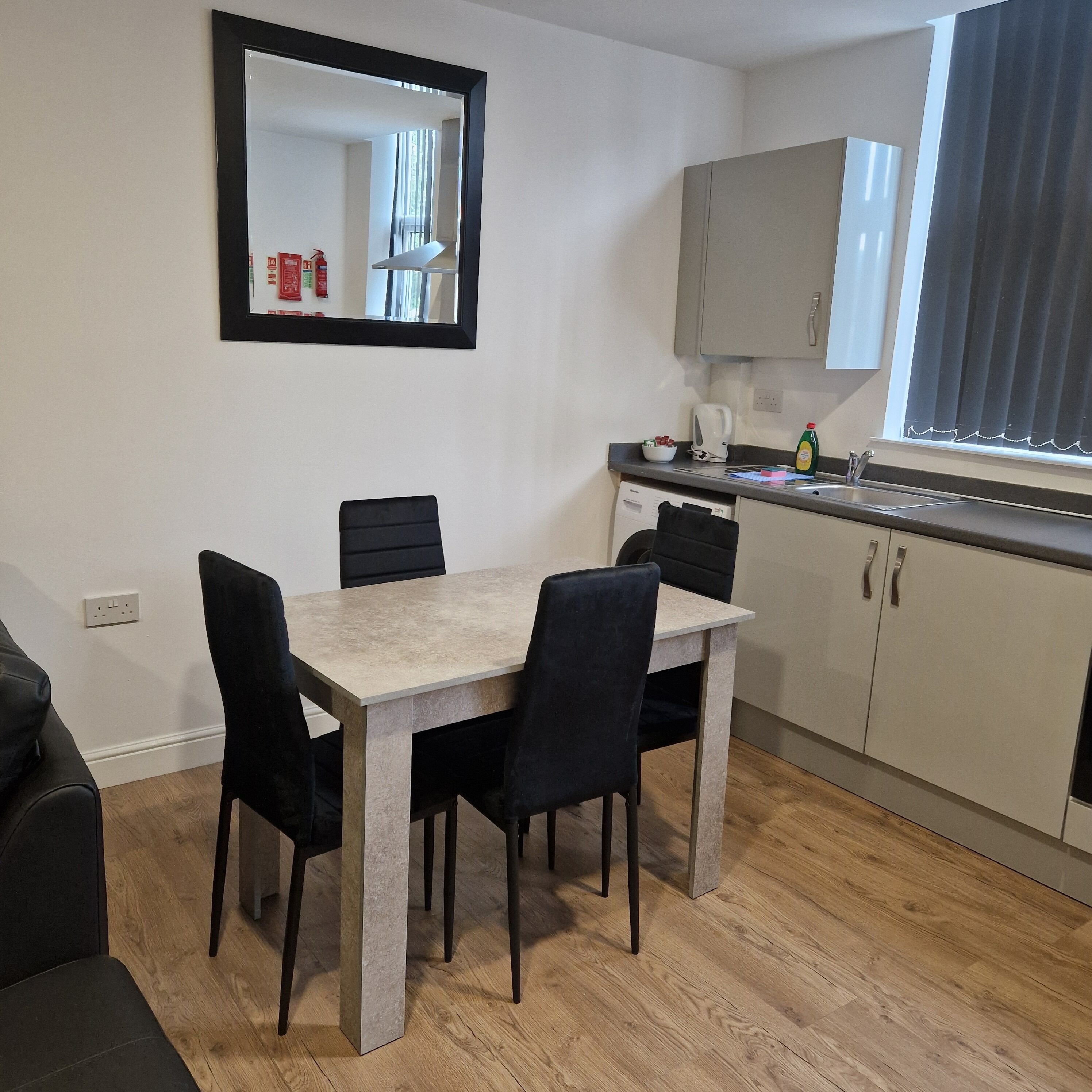Una cocina moderna con una mesa de comedor, sillas y un espejo grande.
