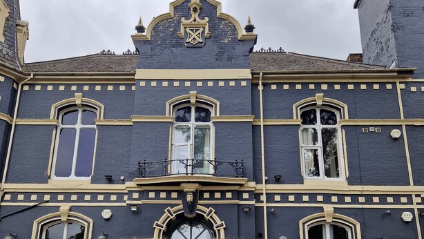 A historic building with a dark facade, ornate architectural details, and a prominent entrance with steps leading up to a blue door. - The Dorchester Hotel (Hull)