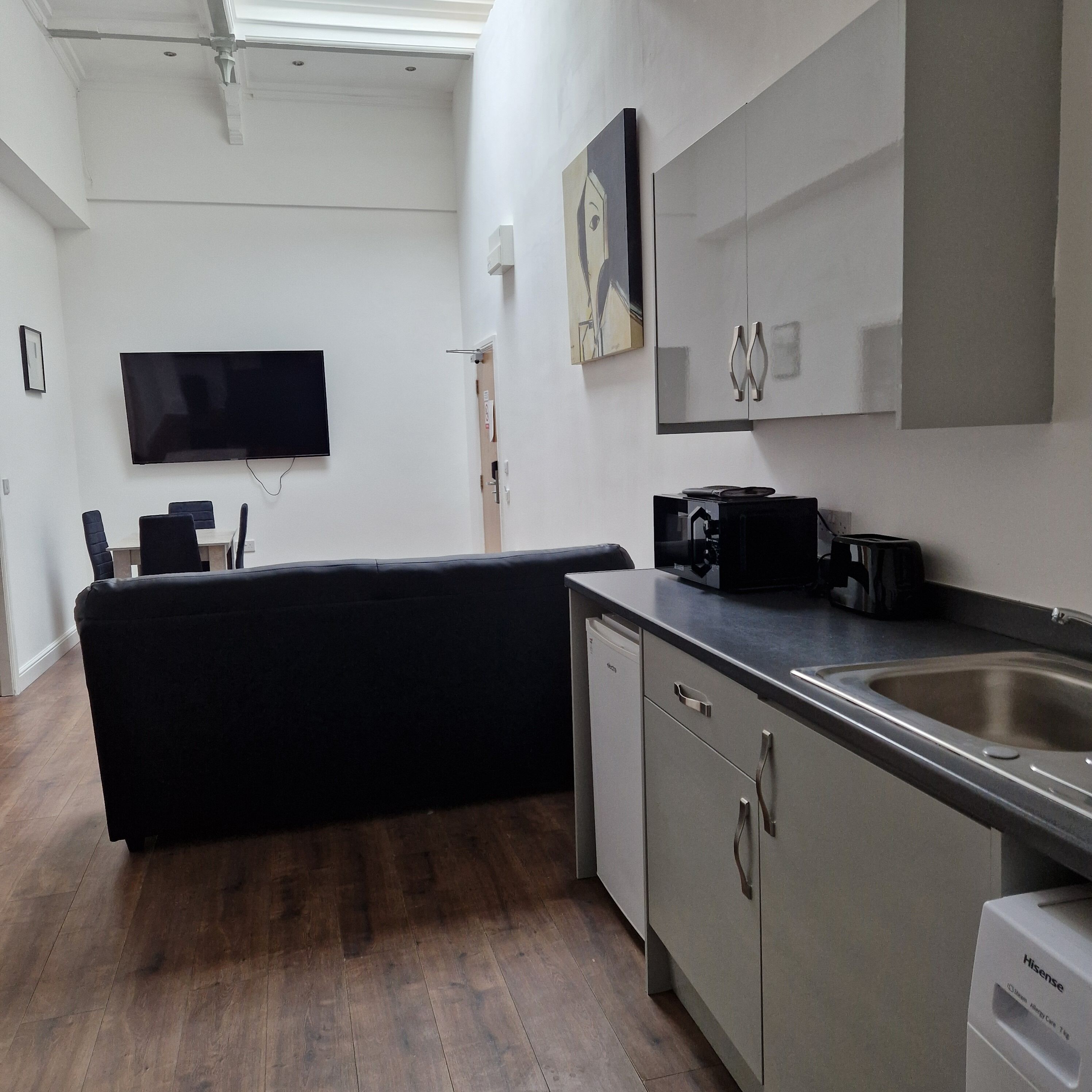 A compact kitchen with a dishwasher, a sink, and a coffee machine.