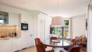 A modern kitchen with white cabinets, a round dining table, and six brown chairs. - Apartment Petra with Pool (Lazise)