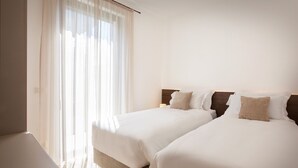 A hotel room with two beds, a bedside table, and a window with sheer curtains. - Apartment Petra with Pool (Lazise)