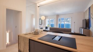 Una cocina moderna con encimera de madera, estufa integrada y comedor con mesa dispuesta para cuatro comensales.
