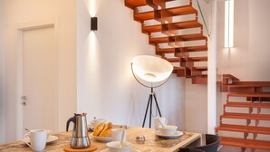 Un comedor con una mesa de madera dispuesta para el desayuno, una cafetera y una lámpara moderna.