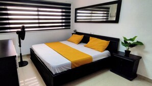 Een verzorgde slaapkamer met een bed, nachtkastjes, een bureau en een potplant.