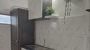 Een keuken met witte marmeren kastjes, een zwart aanrecht, een roestvrijstalen spoelbak en een gasfornuis.