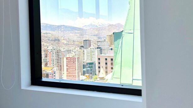 A window with a view of a cityscape and mountains. - Charming 3-bedroom high-rise condo in the safest downtown neighborhood (La Paz)