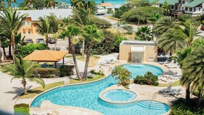 Un complexe hôtelier doté d’une grande piscine, de palmiers et offrant une vue sur l’océan.
