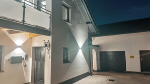A building with a two-story structure, a door, and a small outdoor area with a paved floor. - Bachgeflüster suite, incl. whirlpool, sauna (Bad Kötzting)