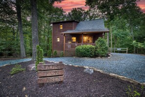 A cabin with a porch, surrounded by trees and a gravel driveway. - S’more Fun - Pets, fenced yard, close to downtown (Blue Ridge)
