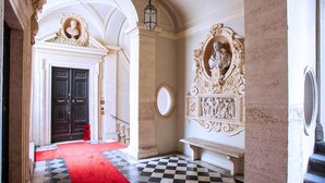 A grand hallway with a checkered floor, a red carpet, and ornate wall decorations. - Palazzo Costaguti – La Dimora del Tempo (Roma)