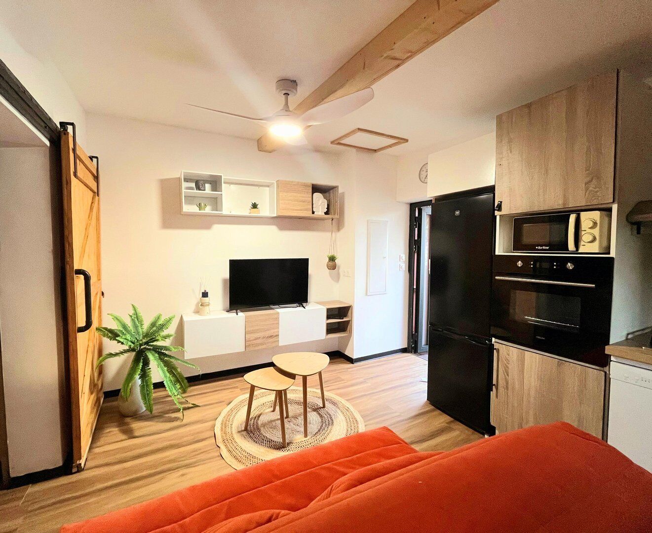 Un espace de vie compact comprenant un coin cuisine, un téléviseur à écran plat, un coin repas et un lit.