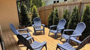En terrasse med fire Adirondack-stole arrangeret i en cirkel, omgivet af en træterrasse og et træhegn.